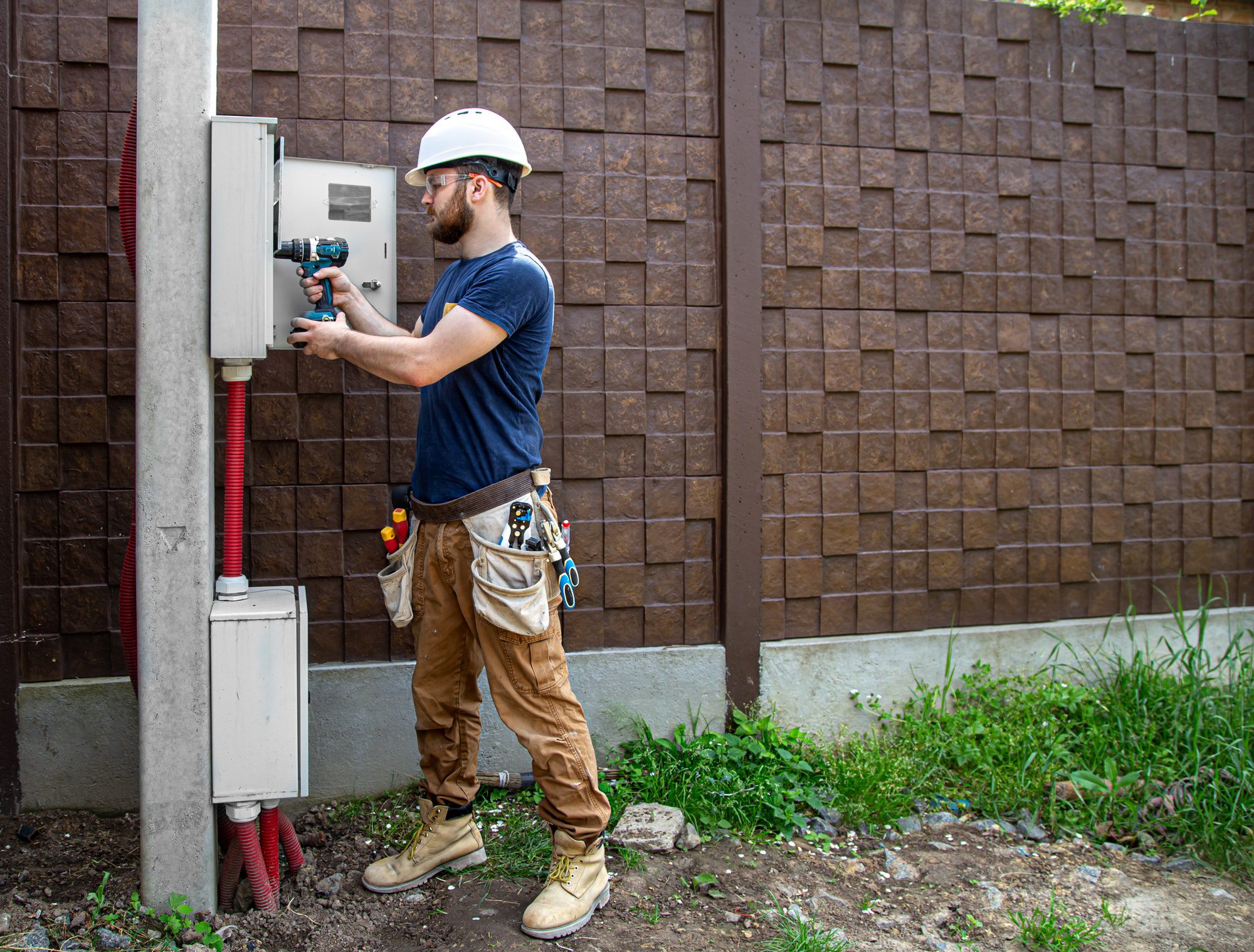 Electrician Builder at work, examines the cable connection in the electrical line.